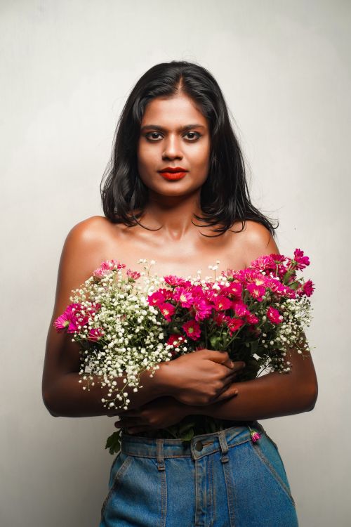 Free Portrait of a woman holding flowers against a neutral background. Stock Photo