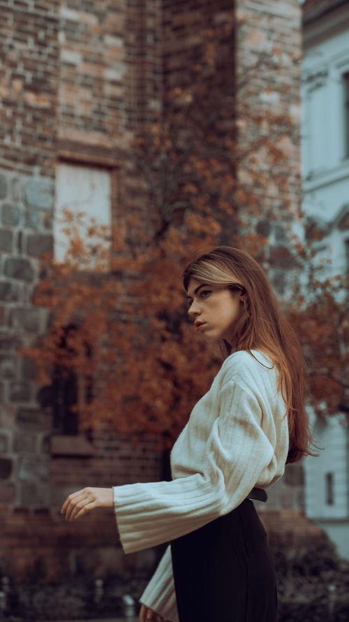 Free Fashionable woman in a white sweater poses on a city street during autumn. Stock Photo