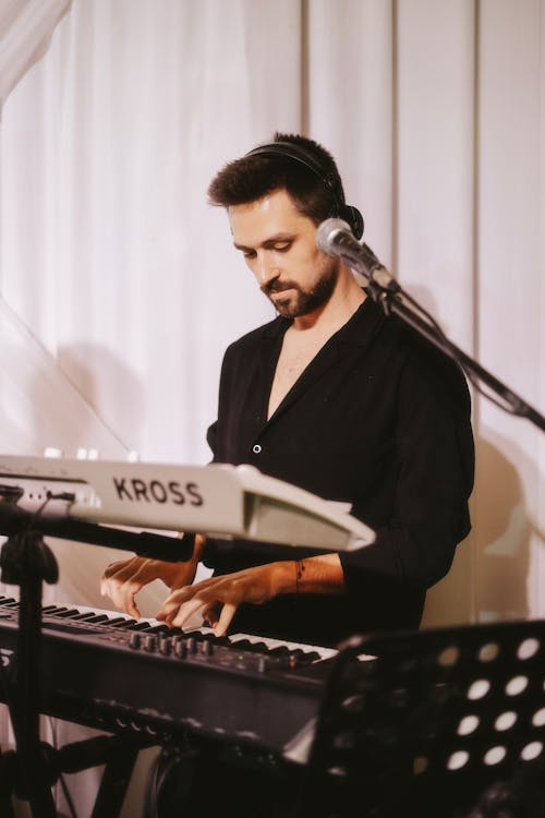 Brunette Man in Black Shirt Playing the Keyboard Instrument