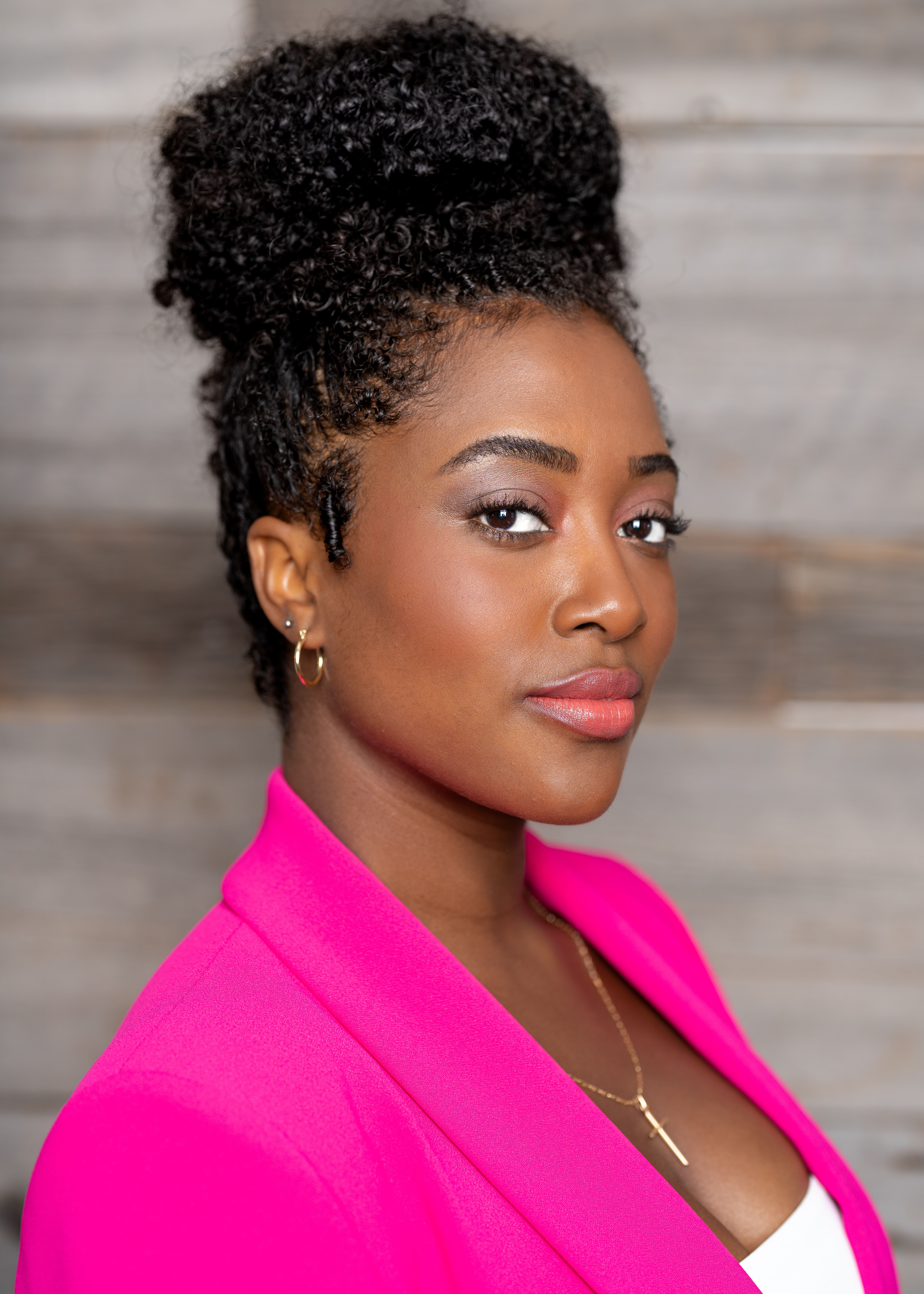 Stylish portrait of a young woman posing confidently in an elegant pink blazer.