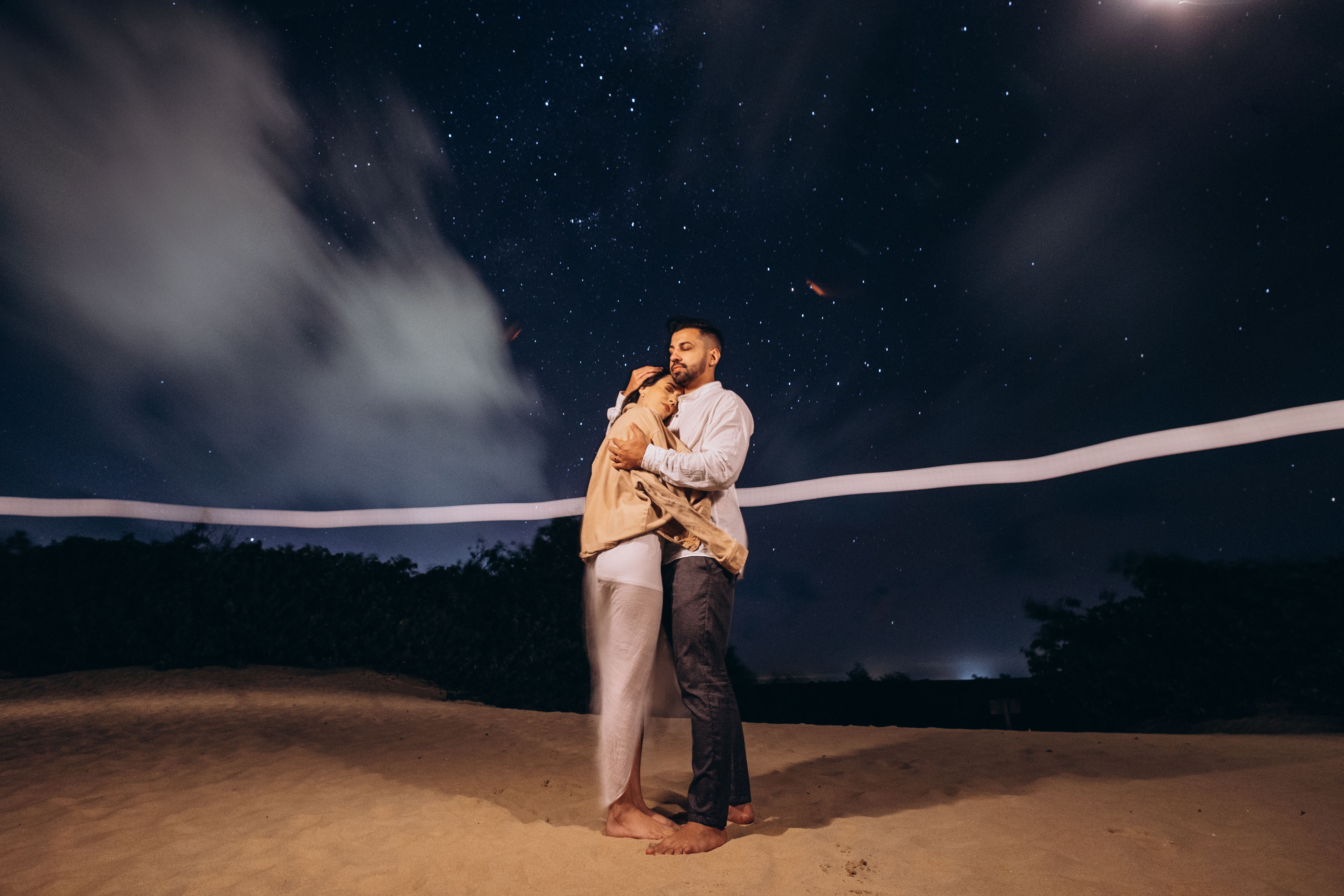 A couple embracing on a starry night beach