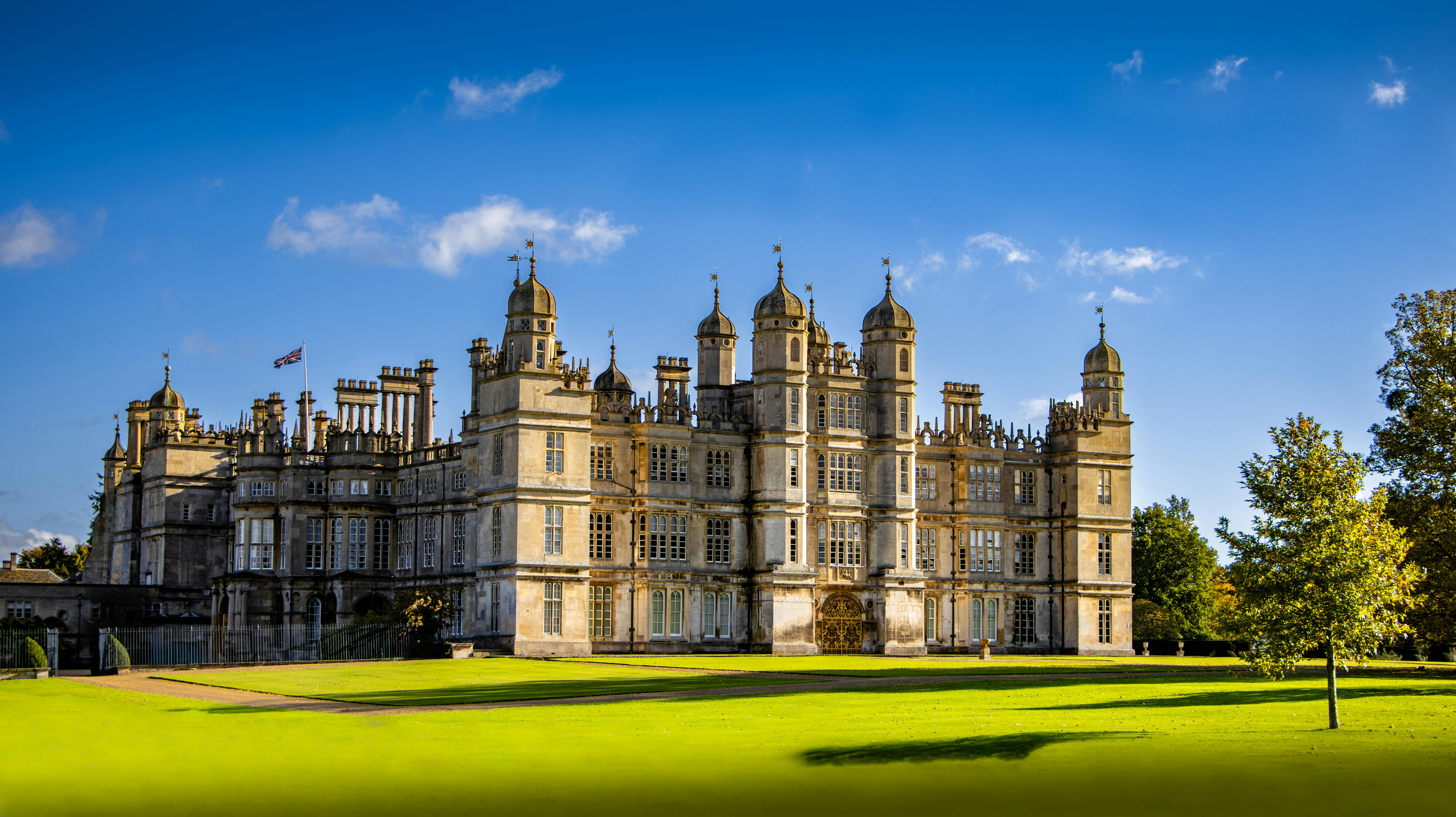 A majestic view of Burghley House under a clear blue sky, showcasing its historic architecture.