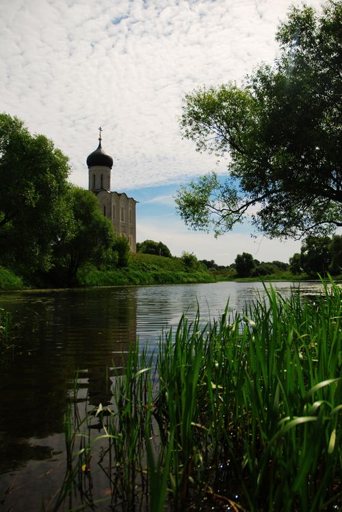 Free Serene view of a historic Russian church by a peaceful river. Stock Photo
