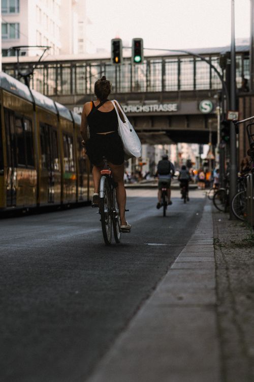 Free Cyclists ride in vibrant Berlin street beside tram and traffic light, showcasing urban life. Stock Photo