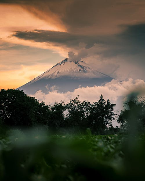 View of a Volcano with Smoke Coming Out of the Top at Sunset 