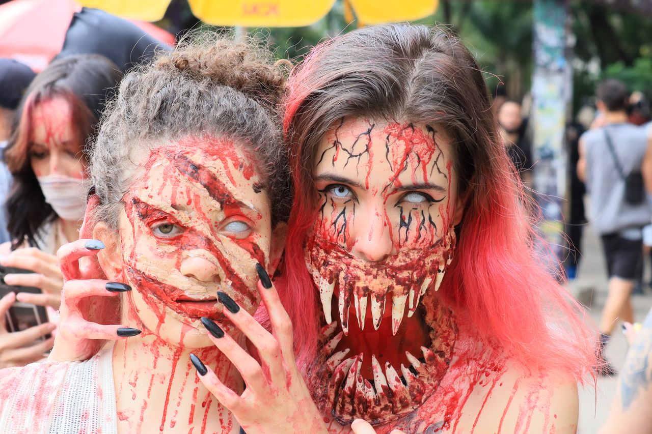 gruesome zombie makeup on two women at a halloween celebration outdoor