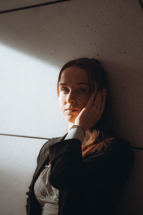 Free Portrait of a woman in soft sunlight against a wall, Berlin, Germany. Stock Photo