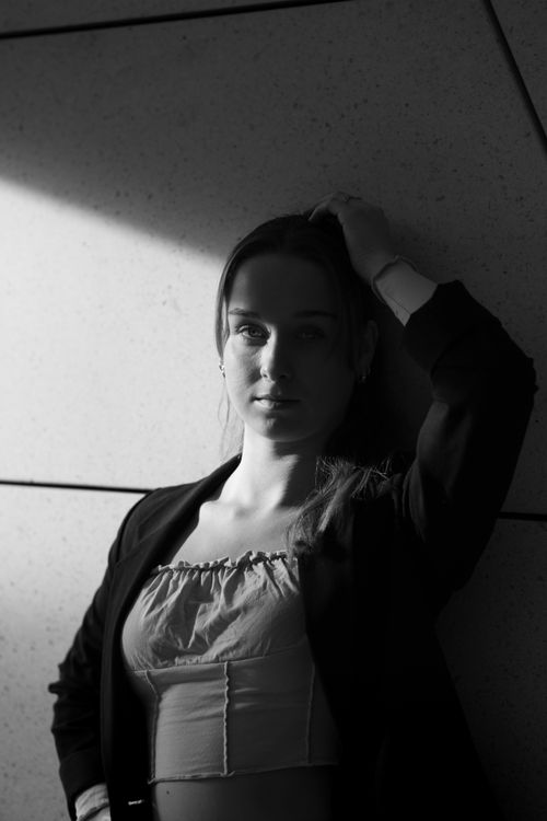 Free Casual black and white portrait of a woman standing against a wall in sunlight. Stock Photo