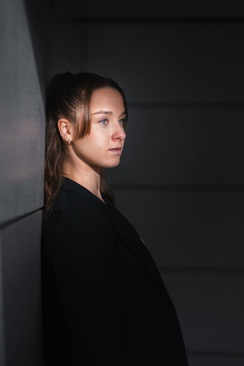 Free Young woman in a black blazer posing against a modern wall in Berlin, Germany. Stock Photo