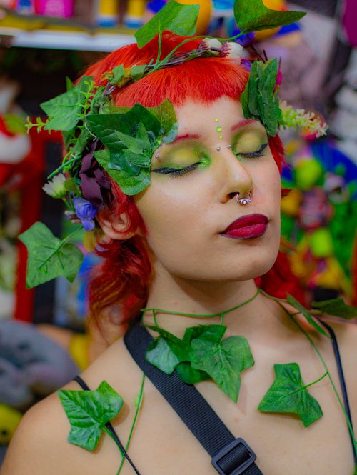 Free A unique fashion portrait featuring a redhead with closed eyes, adorned in leafy accents and colorful makeup. Stock Photo