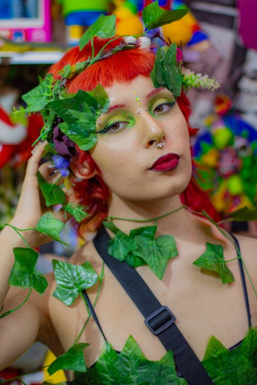 Free Colorful portrait of a young woman with red hair, adorned with fake ivy, showcasing vibrant makeup and a unique costume. Stock Photo