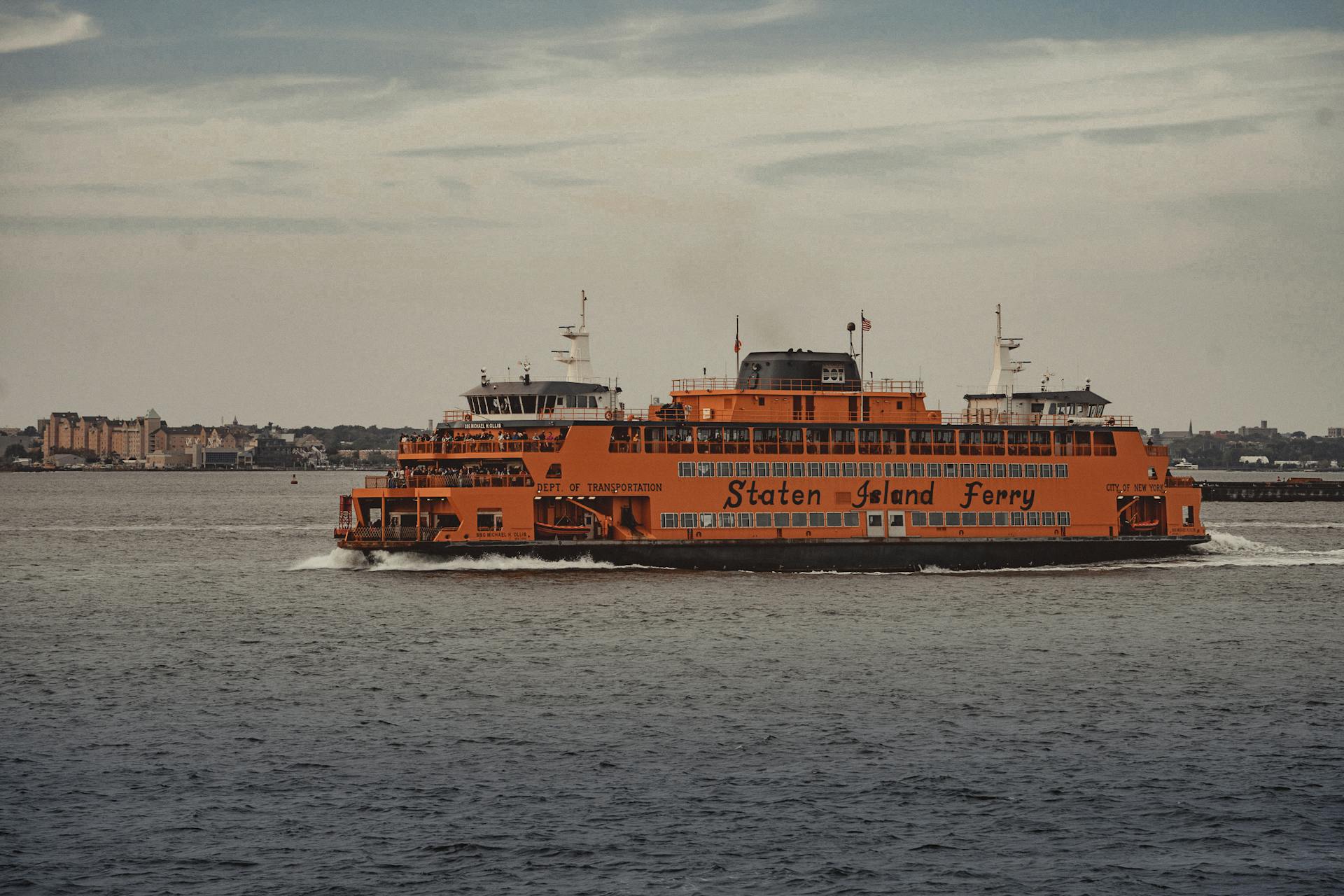 A Staten Island Ferry transporting passengers across New York Harbor with cityscape in the background.