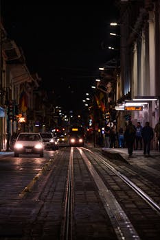 Vibrant city street with tram and pedestrians at night in Cuenca, Ecuador.