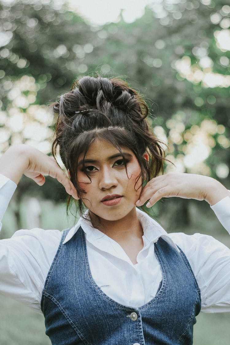 Portrait Of A Young Woman Wearing A White Shirt And Denim Vest Posing Outside 