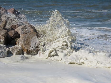 Powerful ocean waves splashing against rocks, creating sea foam and dramatic motion.