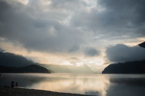 Free Peaceful sunrise over a tranquil lake with misty mountains and scenic nature view. Stock Photo
