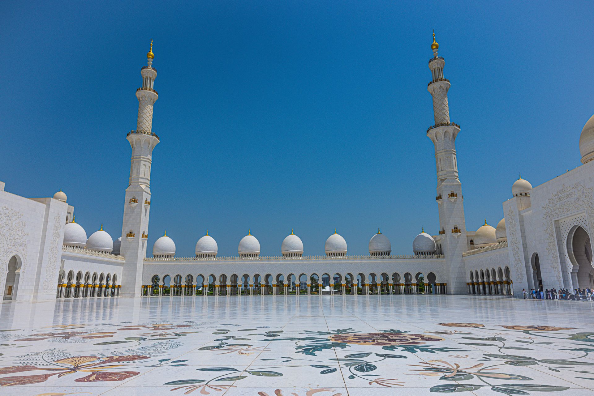 Stunning view of the Sheikh Zayed Grand Mosque's intricate courtyard in Abu Dhabi under a clear blue