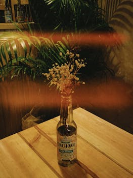 Vintage bottle with flowers in a dimly lit bar interior, creating a warm, moody ambiance.