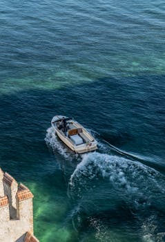 航拍照片中，一艘快艇在清澈的海水中沿着沿海建筑物航行