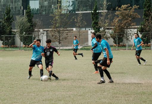 Amateur soccer players competing fiercely on an outdoor field during a daytime match.