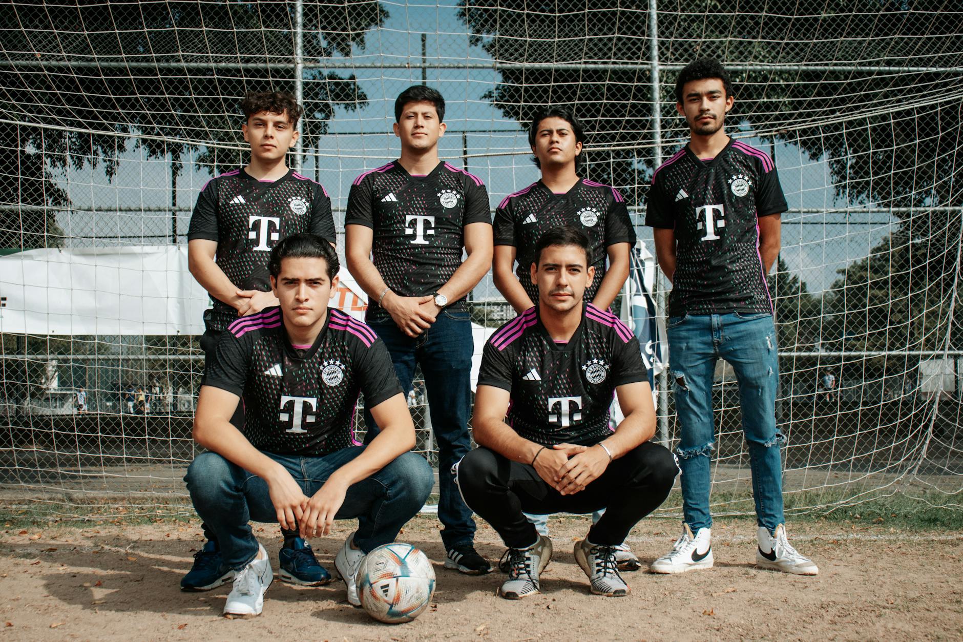 A group of men posing for a photo in front of a soccer net