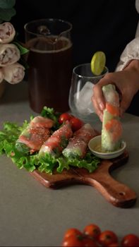 Appetizing spring rolls with dipping sauce on a wooden board, ideal for a healthy lunch.