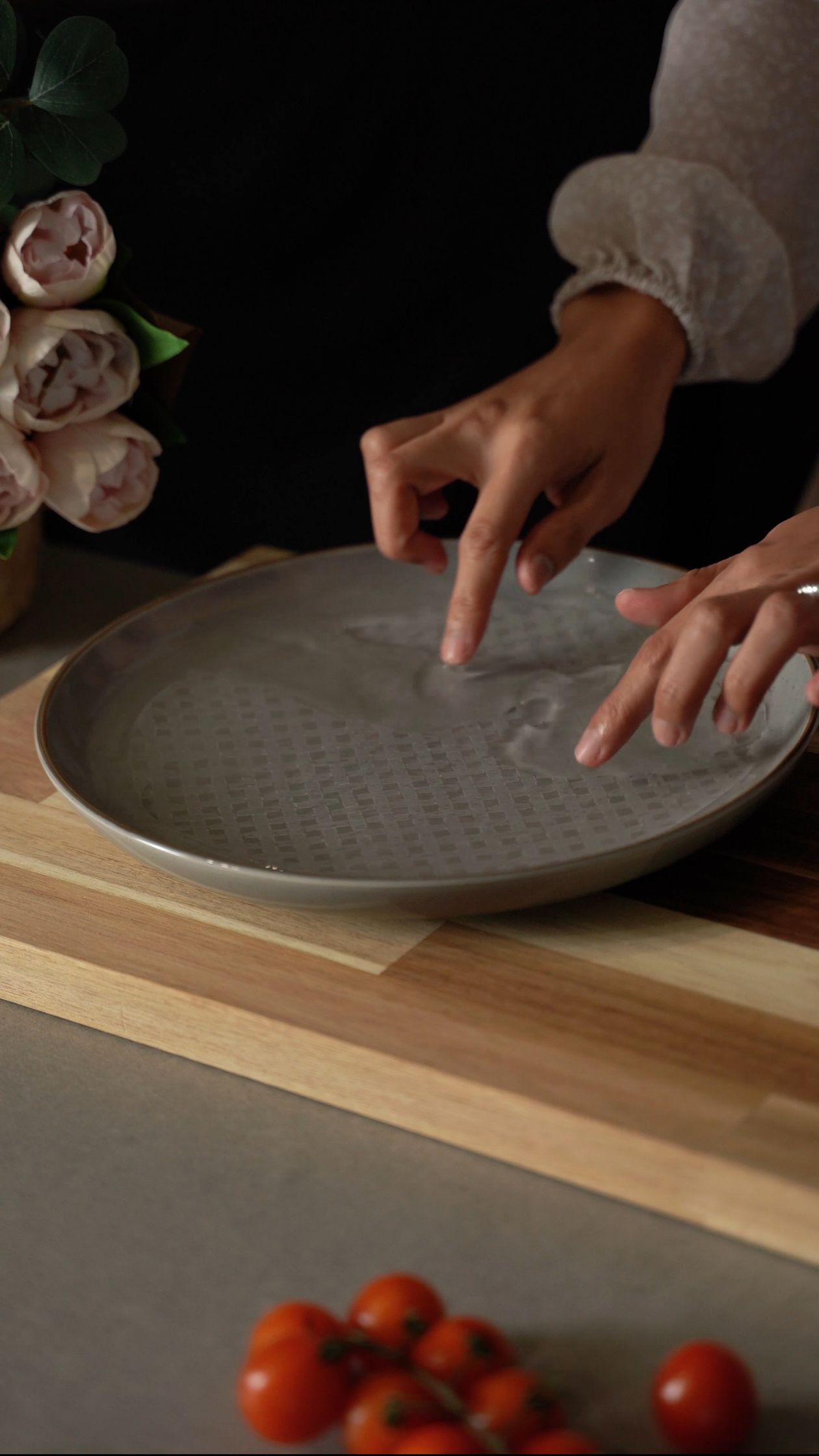 Hands gently pressing wet rice paper onto a plate during spring roll preparation — the same technique used for rice paper scallion pancakes