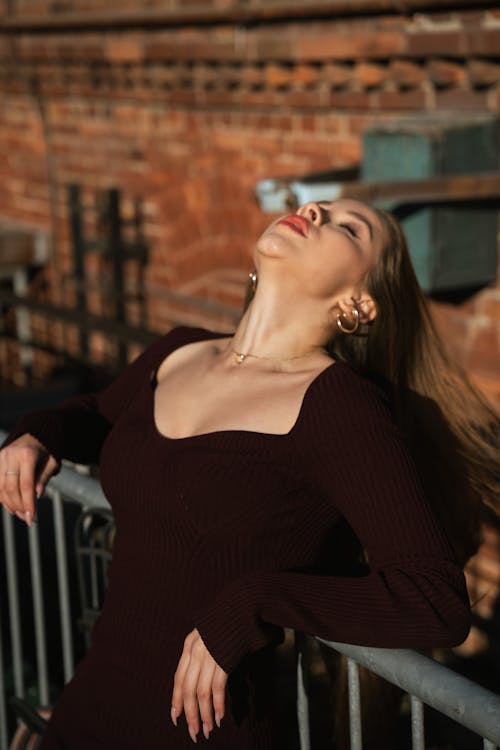 Glamour Woman in Black Dress Posing by Fence