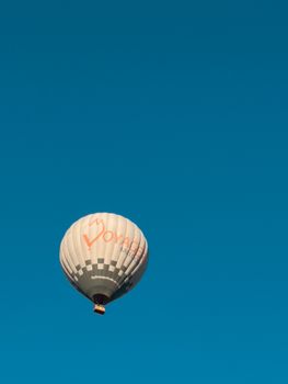 A lone hot air balloon drifts peacefully against a clear blue sky, offering a sense of serene adventure.