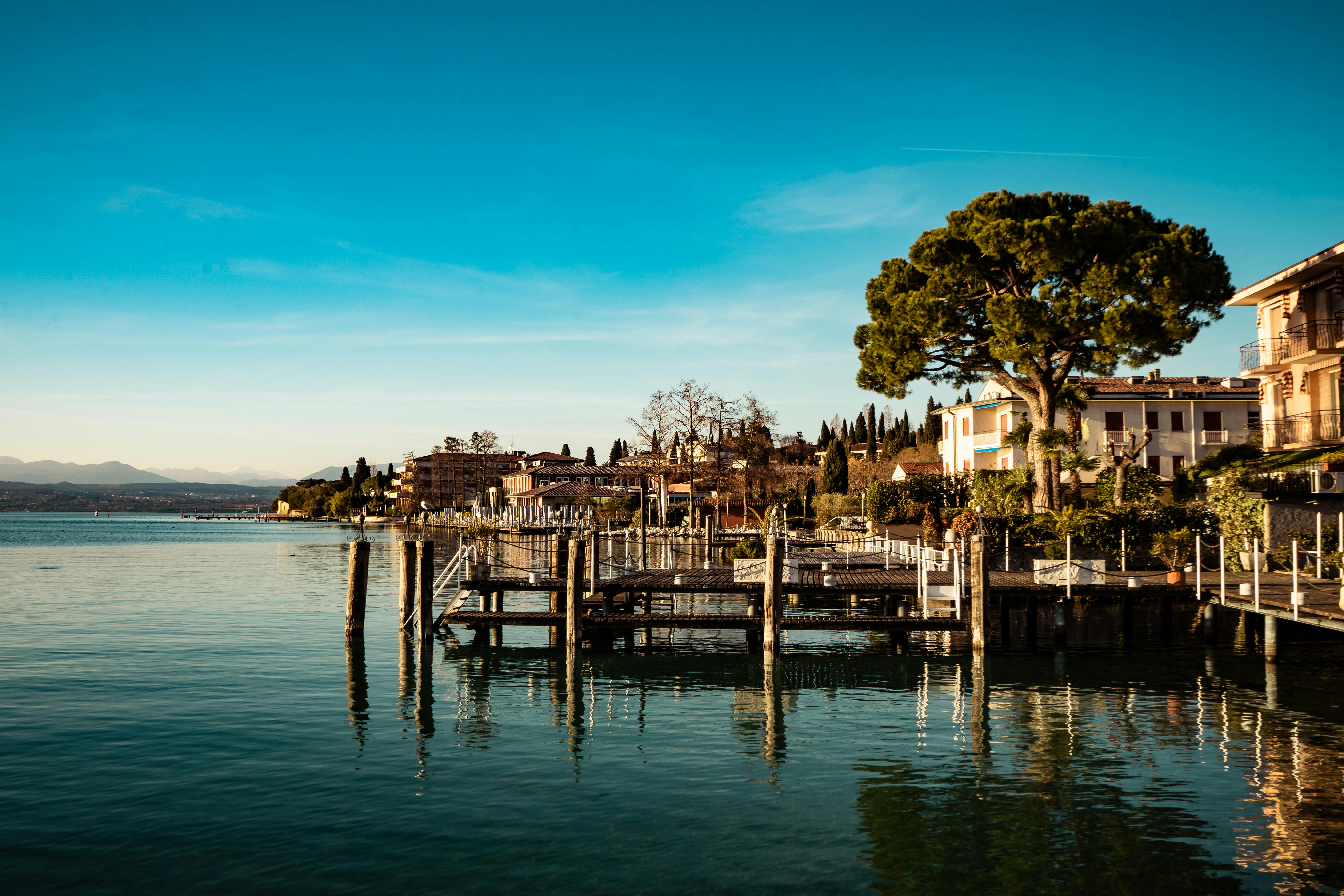 美丽的海滨小镇，湖水倒映着建筑物、树木和码头，天空清澈湛蓝