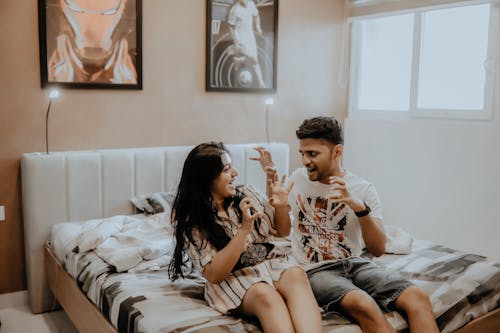 A Couple Sitting on the Bed Having Fun 