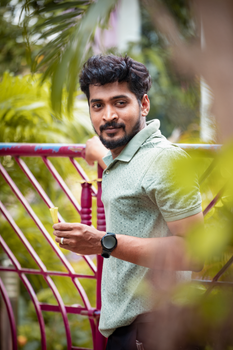 South Asian man in a green polo shirt standing by a fence outdoors in Chennai, India. 19159280