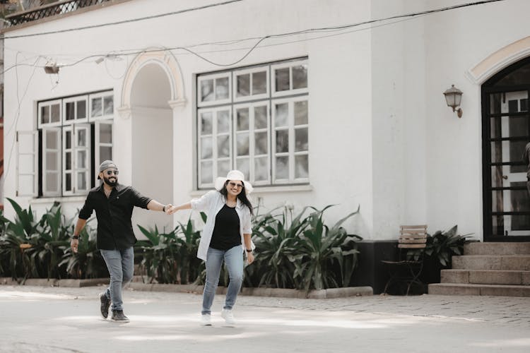 A Couple Holding Hands And Smiling While Walking Outside 