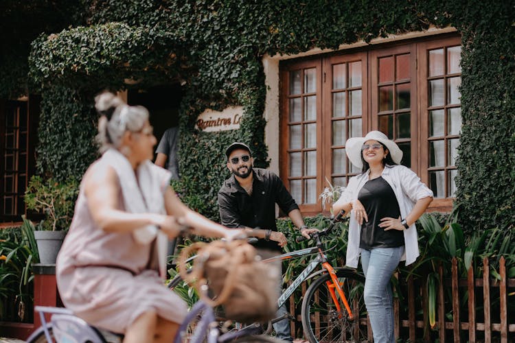 Man And Woman Standing Outside Of A Building With A Bicycle And Smiling 