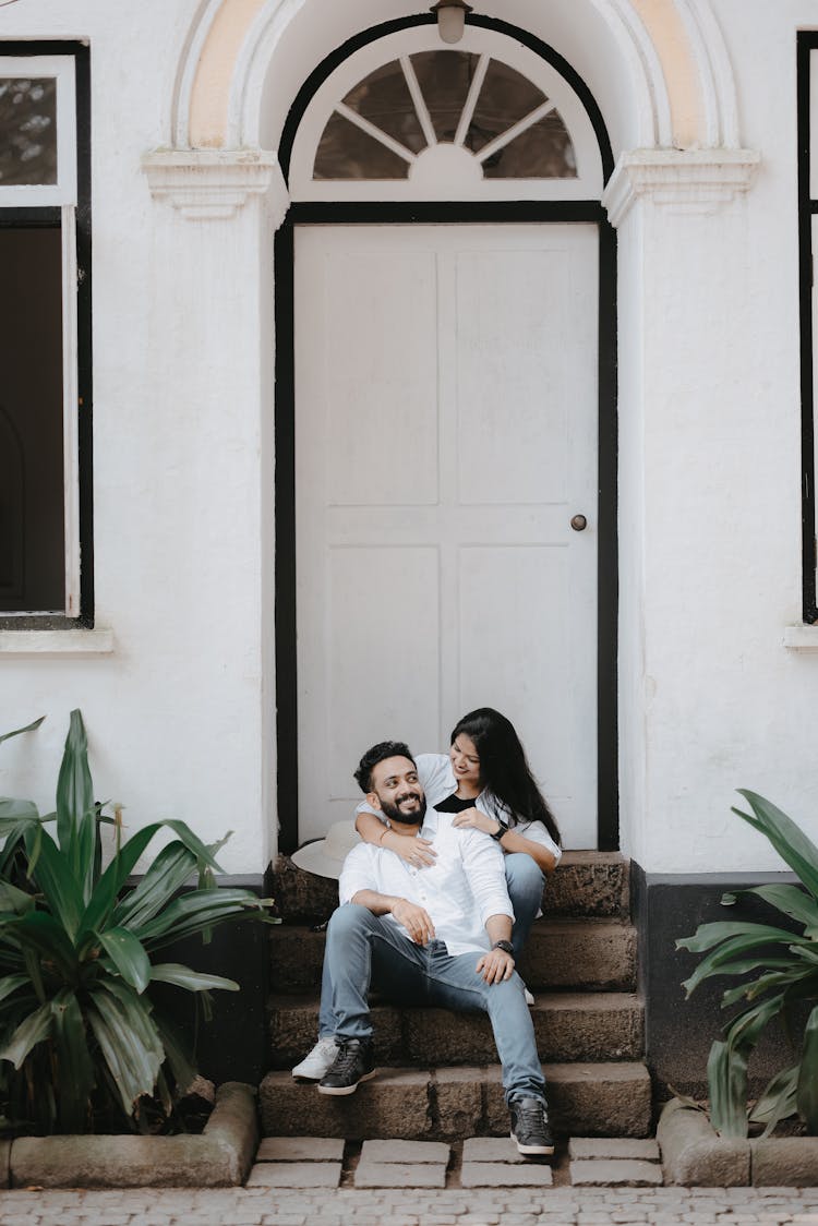 Smiling Couple Sitting On The Steps Of The House