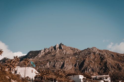Free Stunning view of rocky mountain under clear sky with houses and palm trees in foreground. Stock Photo