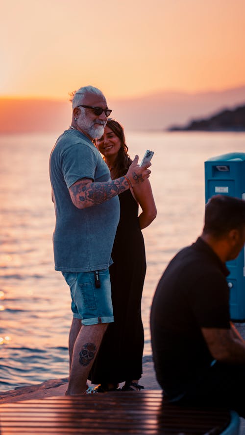 Smiling Couple Taking Selfie on Sea Shore at Sunset