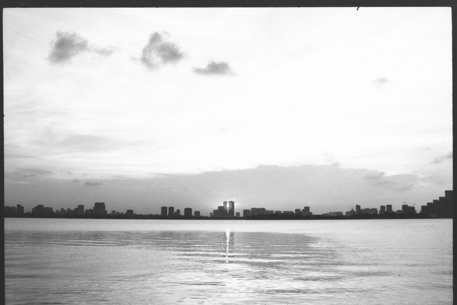 Black and white view of Hanoi city skyline at sunset reflecting over the tranquil lake.