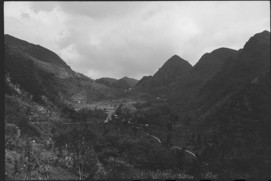 A captivating black and white image depicting a serene mountain valley shrouded in mist and fog.