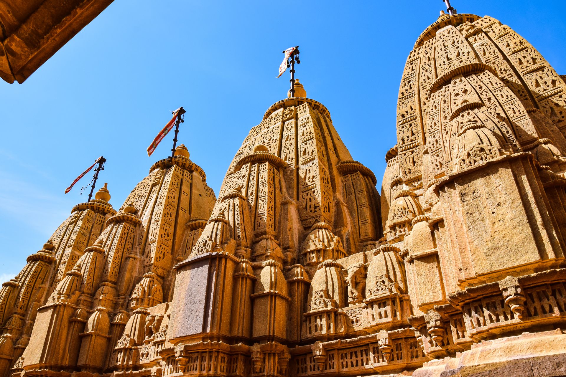 Beautiful temple spires with intricate carvings against a clear blue sky, showcasing Indian architecture.