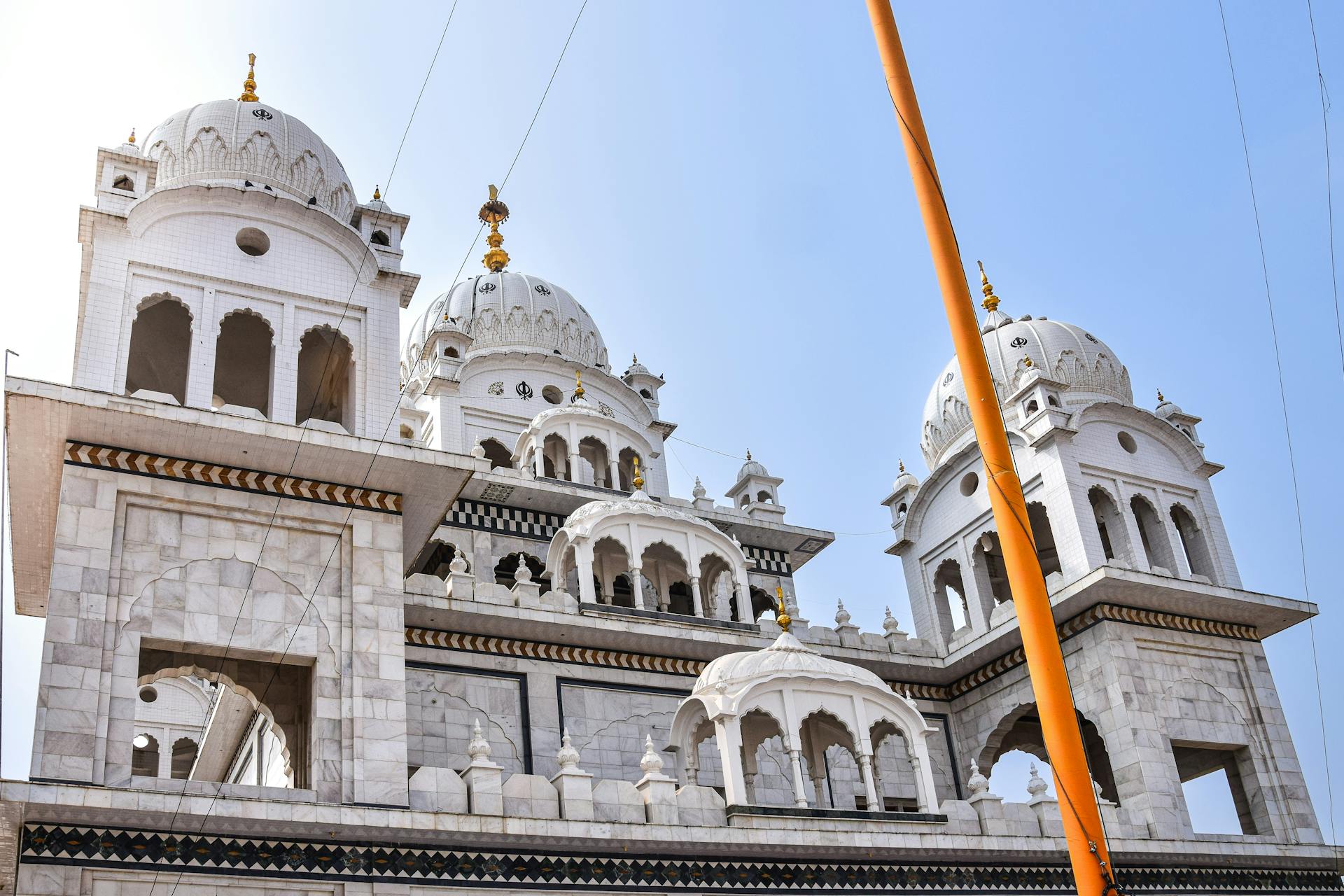 A stunning view of a traditional Indian Gurudwara with intricate marble domes under a clear sky.