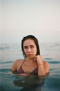 A serene portrait of a woman with wet hair in the ocean, creating a peaceful ambiance.