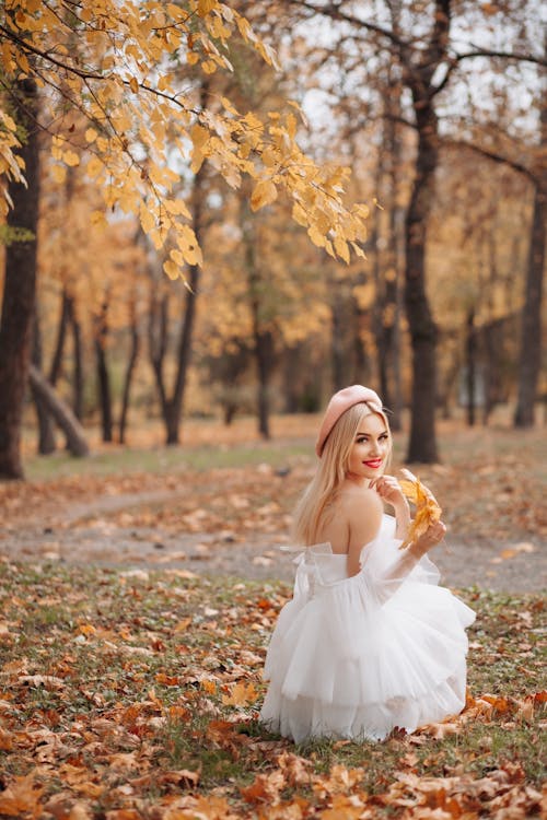 Young Woman in a White Tulle Dress Posing in a Park in Autumn 