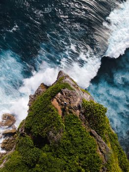 Stunning aerial shot of cliffside in Bali with dramatic ocean waves below.