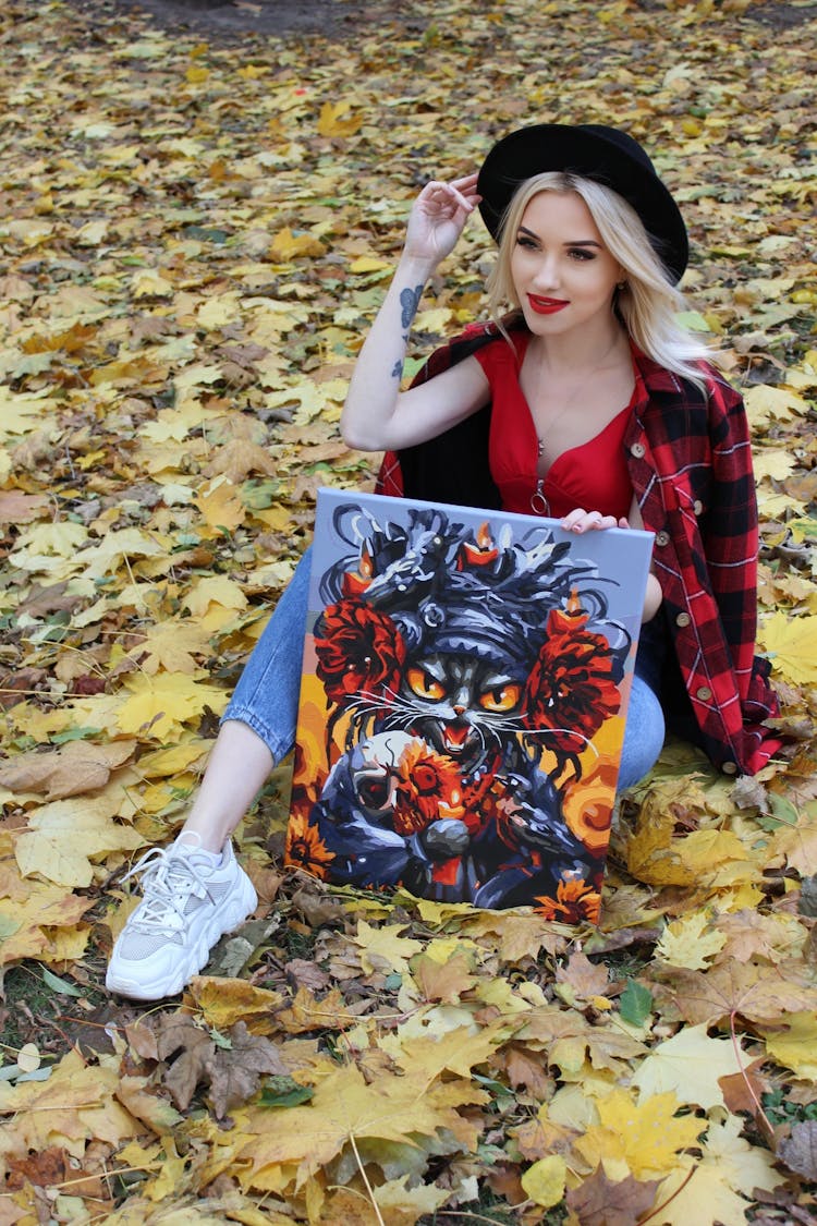 Blonde Woman Sitting With Painting In Autumn