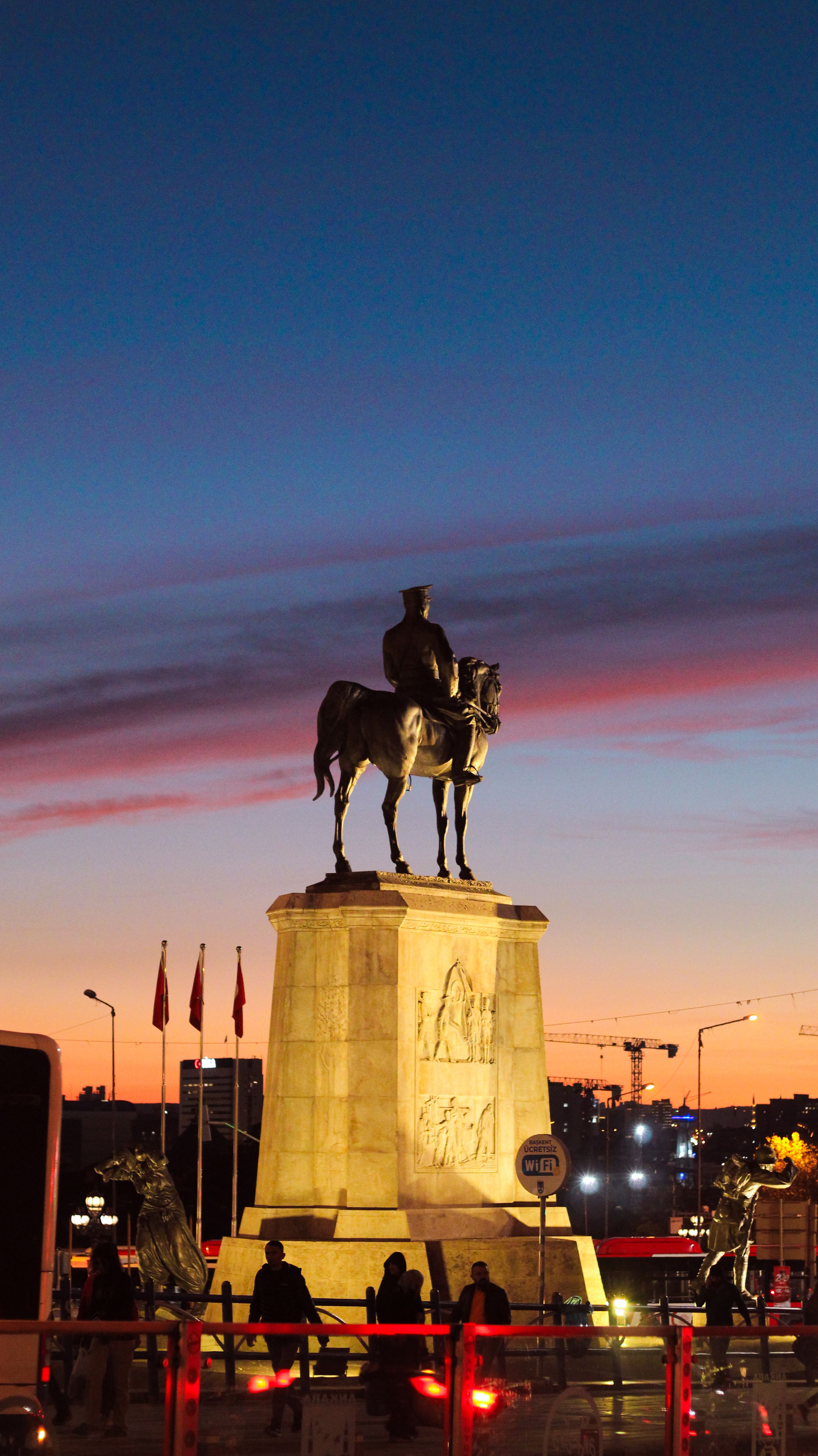 Bronze Ataturk statue in Ankara framed by a vibrant sunset sky, symbolizing Turkish history.