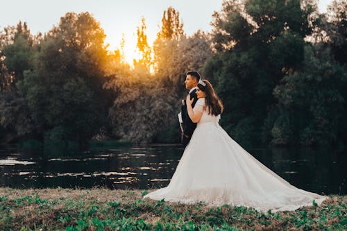 Bride in Wedding Dress Embracing Groom on Lakeside