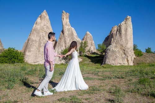 Woman in White Dress Walking with Man by Boulders