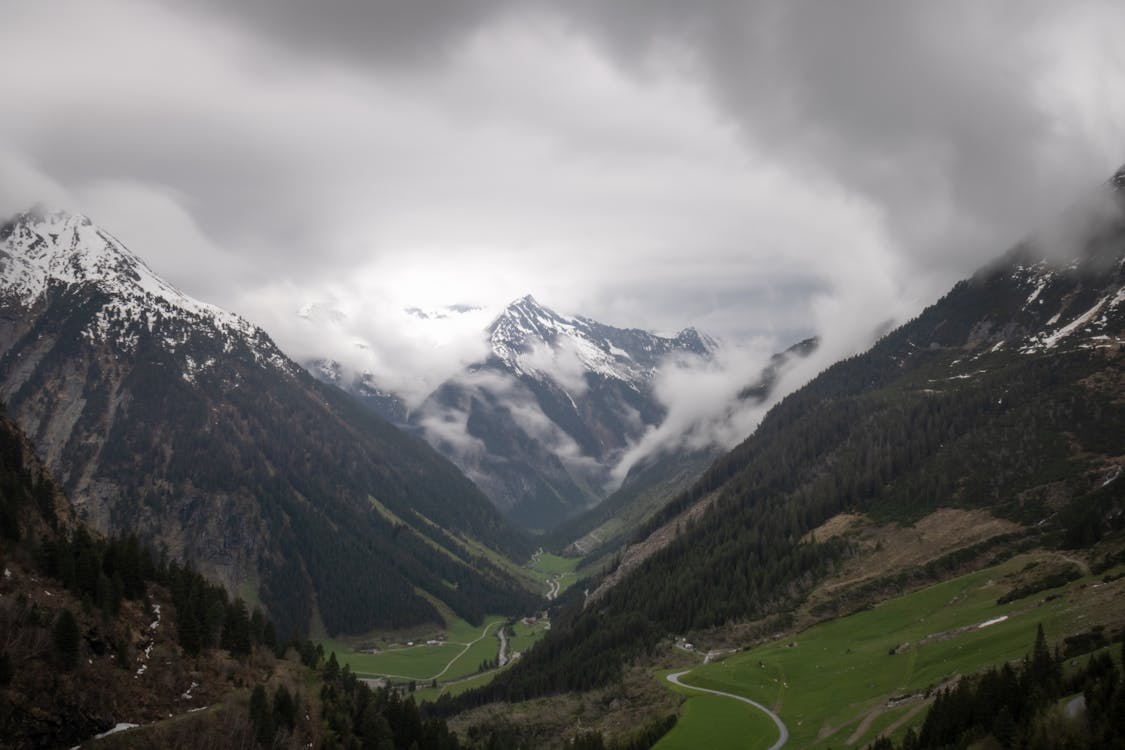 A valley with mountains and clouds in the background