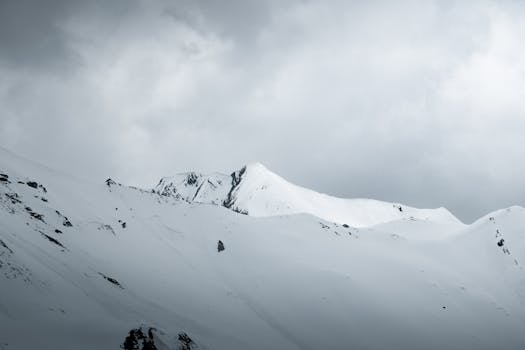 A stunning view of snow-covered mountain peaks under cloudy skies in Tux, Tirol, Austria.
